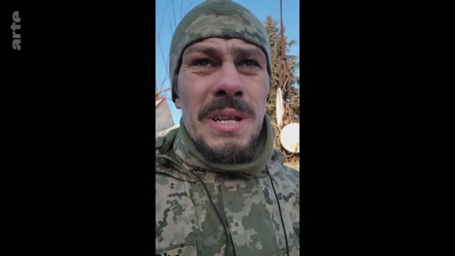 Un soldat ukrainien en tenue de camouflage et bonnet militaire s'adresse à la caméra lors d'un témoignage sur le terrain, illustrant la situation du conflit en Ukraine.