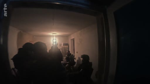 Des soldats ukrainiens en tenue de combat sont rassemblés dans un bunker faiblement éclairé, illustrant la vie quotidienne des troupes sur le front en Ukraine.