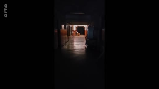 Vue en perspective d'un long couloir sombre et peu éclairé à l'intérieur d'un hôpital militaire, évoquant une atmosphère de convalescence ou de soins médicaux.