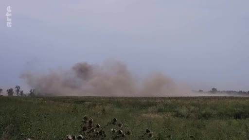 Une explosion de poussière et de terre dans un champ ouvert, illustrant un conflit ou des manœuvres militaires.