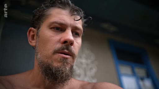 Un homme barbu, filmé en gros plan, semble plongé dans une réflexion profonde ou une introspection, illustrant le thème de la libération personnelle.