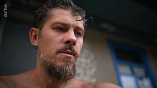 Gros plan sur un homme barbu à l'air pensif, illustrant une quête de libération personnelle dans un contexte documentaire.