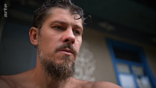 Un homme barbu, au regard pensif et mélancolique, est filmé en gros plan dans une séquence évoquant le cheminement vers la libération personnelle.