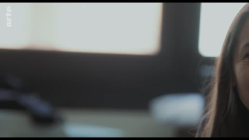 Une femme sourit pendant une conversation, illustrant une scène de dialogue intime entre une mère et son fils.