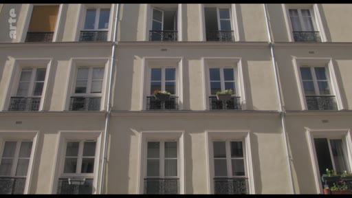 Vue en contre-plongée de la façade d'un immeuble résidentiel parisien de style haussmannien avec ses fenêtres à balconnets en fer forgé. Ce type d'architecture est emblématique du paysage urbain de Paris.