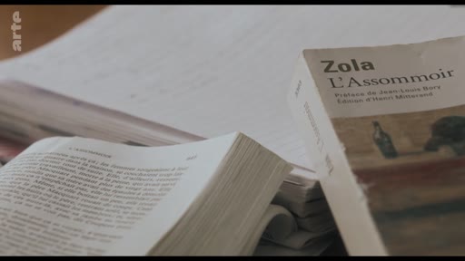 Gros plan sur la couverture et les pages intérieures du roman L'Assommoir de l'écrivain français Émile Zola, illustrant une analyse littéraire de l'œuvre naturaliste.