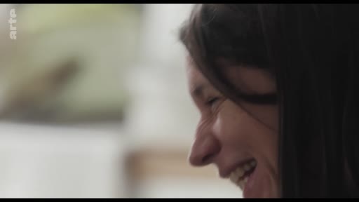 Gros plan sur le visage d'une femme souriante, capturée lors d'un moment de complicité ou d'échange informel.