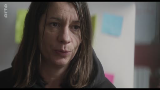 Gros plan sur une femme s'exprimant face caméra lors d'une interview, avec des post-its colorés en arrière-plan.