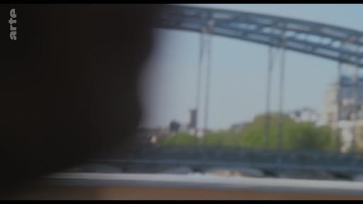 Vue en plan large d'un pont métallique emblématique de Paris, filmé depuis l'intérieur d'un véhicule ou d'un bâtiment, illustrant une ambiance urbaine.