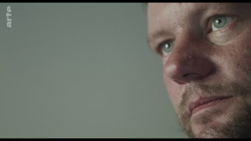 Gros plan sur le visage d'un homme exprimant une émotion intense ou une réflexion profonde, dans un contexte de témoignage ou d'interview.