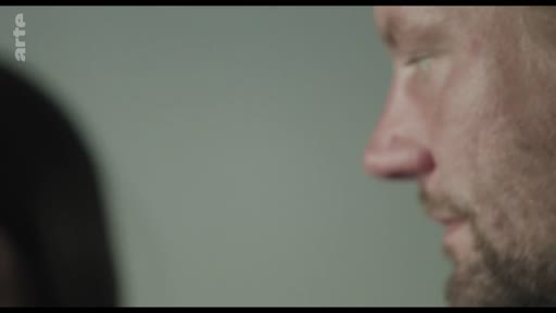 Gros plan sur le visage d'un homme barbu, exprimant une émotion profonde ou une réflexion intérieure lors d'une séquence narrative.