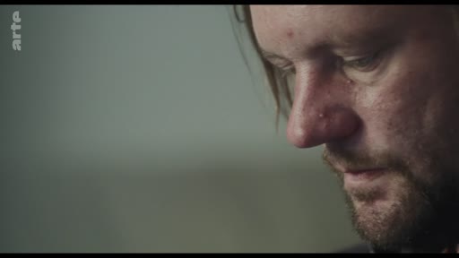 Gros plan sur le visage d'un homme exprimant une émotion intense ou de la vulnérabilité lors d'une discussion, capturé dans un style documentaire.