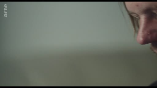 Gros plan sur le visage d'un homme lors d'une séquence de discussion, illustrant un moment de vulnérabilité ou d'échange intime.