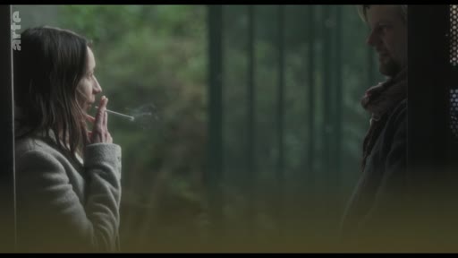 Une femme et un homme se font face dans un cadre intimiste, la femme tenant une cigarette à la main. Cette scène illustre une interaction personnelle entre deux personnages dans un environnement extérieur.