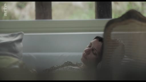 Une femme est allongée dans une baignoire, dans une atmosphère calme et contemplative.