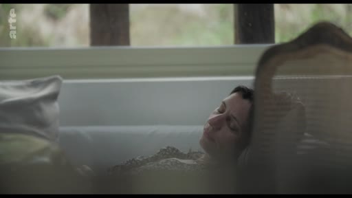 Une femme est allongée et semble se reposer ou méditer dans une pièce lumineuse, dans une atmosphère calme et contemplative.