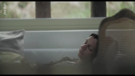 Une femme est allongée dans une baignoire, dans une atmosphère calme et contemplative.