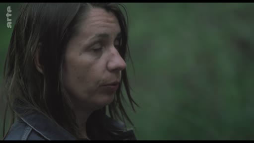 Gros plan sur le visage d'une femme, filmée en extérieur dans une ambiance sombre et mélancolique, lors d'une séquence de tournage.