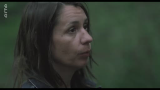 Une femme, filmée en gros plan, s'exprime dans un environnement extérieur lors d'une séquence de production audiovisuelle.