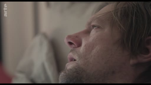 Gros plan sur le visage d'un homme à l'air fatigué ou préoccupé, illustrant une scène de tension domestique ou de soin.