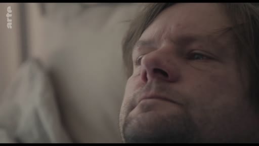 Gros plan sur le visage d'un homme d'âge moyen, exprimant une émotion de fatigue ou de réflexion, dans un contexte de vie quotidienne ou de soins à domicile.