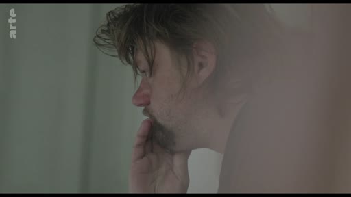 Un homme au visage marqué par la tristesse ou la préoccupation, filmé en gros plan, exprime une détresse psychologique profonde.