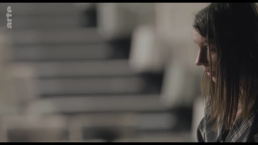 Une femme est filmée de profil dans un intérieur, lors d'une séquence de conversation sur un collègue.