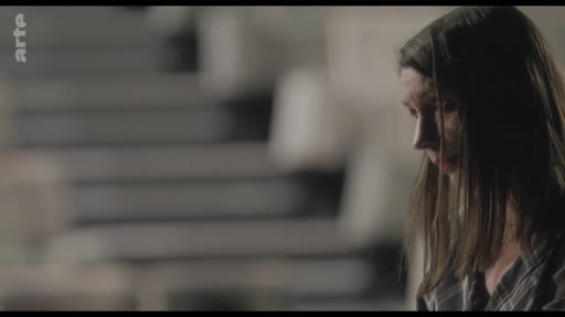 Une femme, vue de profil, semble pensive ou préoccupée lors d'une discussion sur un collègue.