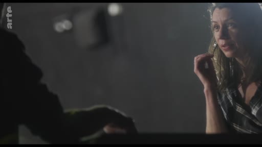 Une femme est filmée en gros plan lors d'une répétition théâtrale, engagée dans une discussion ou une critique artistique.