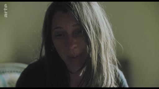 Une femme aux cheveux longs s'exprime lors d'une interview, illustrant un moment de confession ou de témoignage personnel.