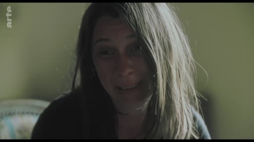 Une femme s'exprime avec émotion lors d'un entretien filmé, illustrant une séquence de confession ou de témoignage personnel.