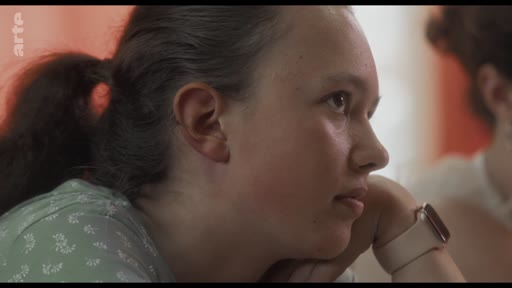 Une jeune femme participe à un atelier, écoutant attentivement les échanges. Elle porte une montre connectée et semble réfléchir au contenu de la session.