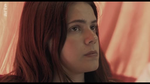 Une jeune femme aux cheveux roux est filmée en gros plan alors qu'elle écoute une discussion sur le traumatisme dans le cadre d'un cours.