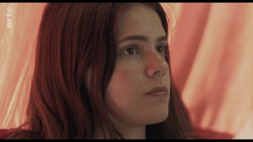 Une jeune femme aux cheveux roux est filmée en gros plan lors d'une discussion en classe portant sur le thème des traumatismes. Elle semble écouter avec attention, illustrant le climat de réflexion et d'échange au sein du groupe.