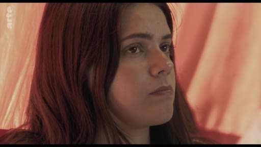 Une jeune femme aux cheveux roux est filmée en gros plan lors d'une discussion en classe portant sur le thème des traumatismes.