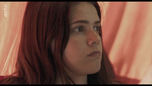 Une jeune femme aux cheveux roux écoute avec attention lors d'une discussion en classe portant sur le thème des traumatismes.