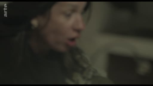 Gros plan sur une femme s'exprimant avec émotion, illustrant une scène de confrontation ou de débat intense.