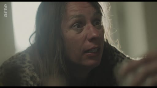 Une femme au regard intense et inquiet lors d'une scène de tension domestique, capturée dans un plan rapproché.