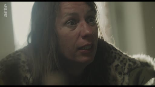 Une femme au regard intense et inquiet s'exprime lors d'une scène de tension domestique, capturée dans un plan serré. L'image souligne l'émotion forte et le conflit dramatique au cœur de cette séquence.