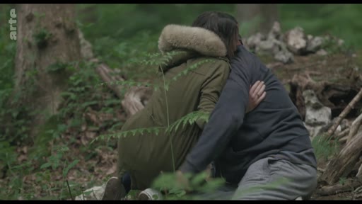 Un homme et une femme s'enlacent tendrement dans un environnement forestier, illustrant un moment de réconfort en pleine nature.