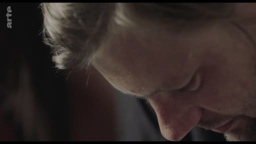 Gros plan sur le visage d'un homme, le regard tourné vers le bas, dans une séquence de dialogue sur les limites professionnelles et personnelles.